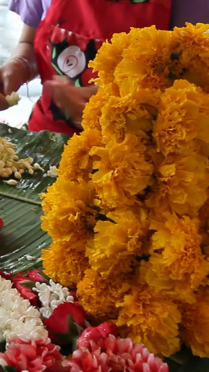 Marigold and jasmine garlands being made at a flower stall